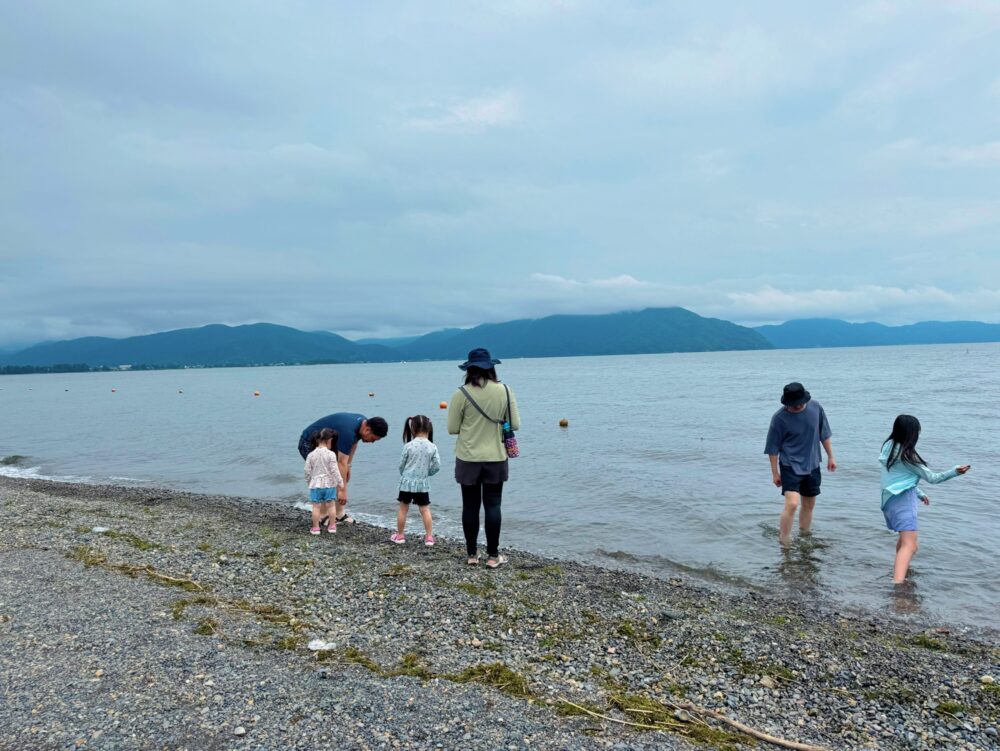 曇り空の今津浜で琵琶湖に入る家族