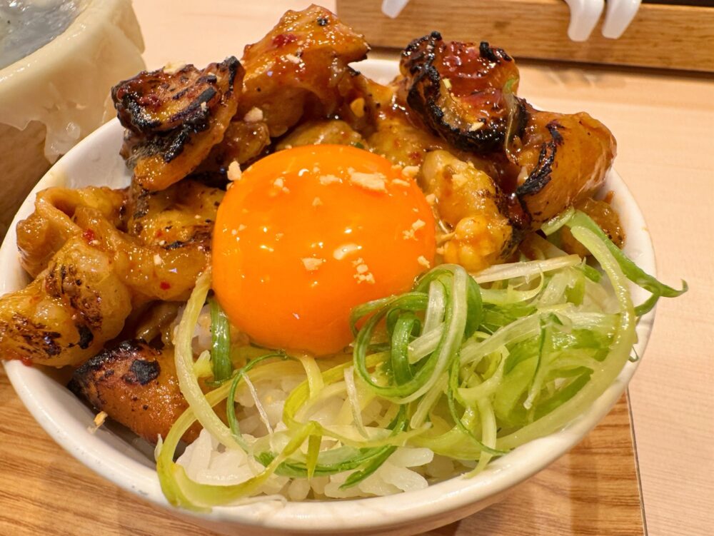 make noodle かしぐの旨辛牛ホルモン丼。炙り目のついたホルモンと卵黄、ねぎ